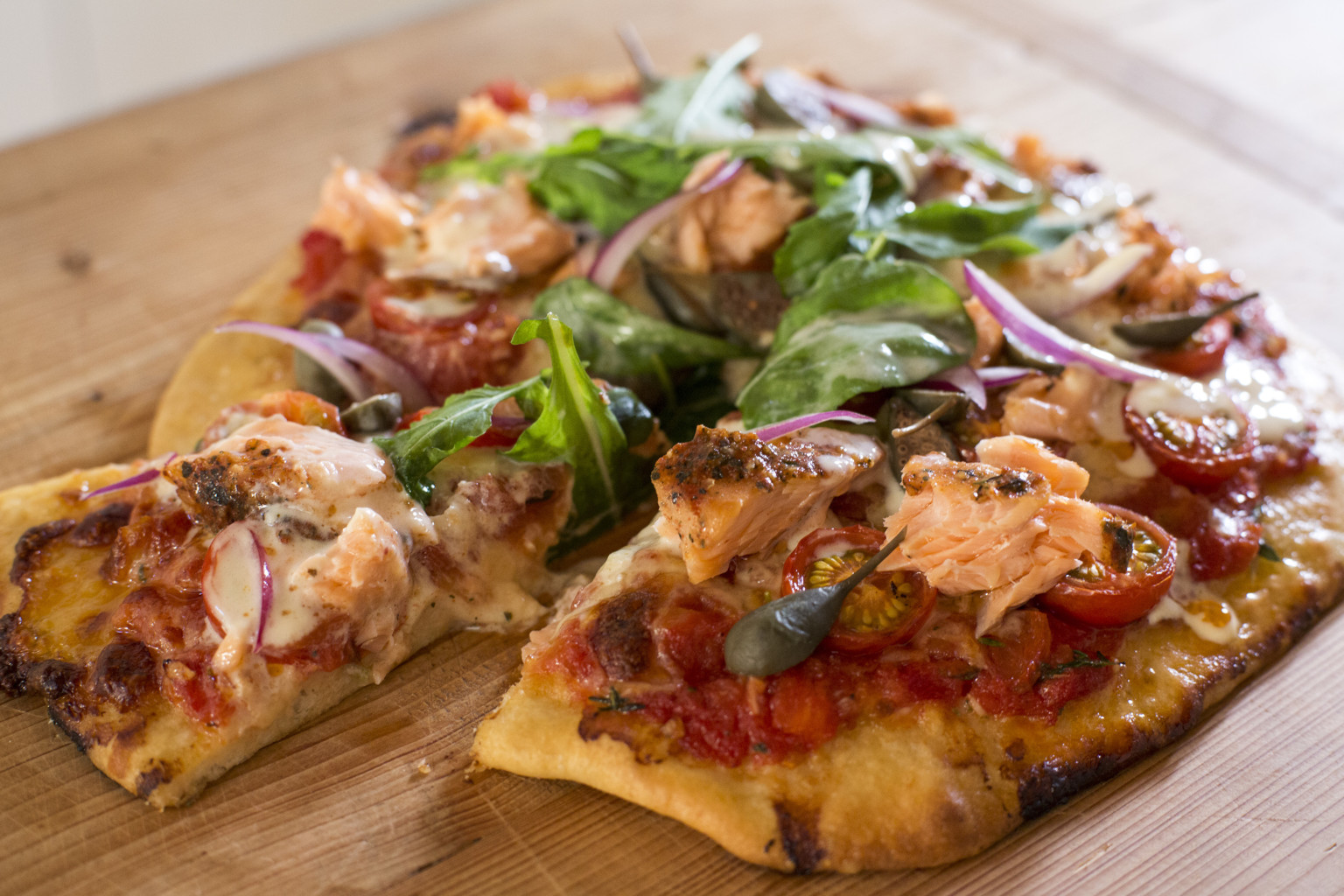 Smoked salmon pizza with tomato, rocket, capers and lemon creme Nadia Lim